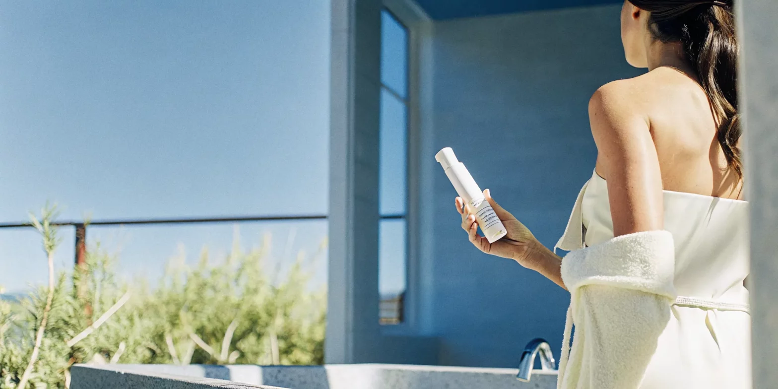 Woman with healthy brunette hair applying hair treatment in a modern bathroom